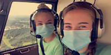 Two girls in masks in helicopter.